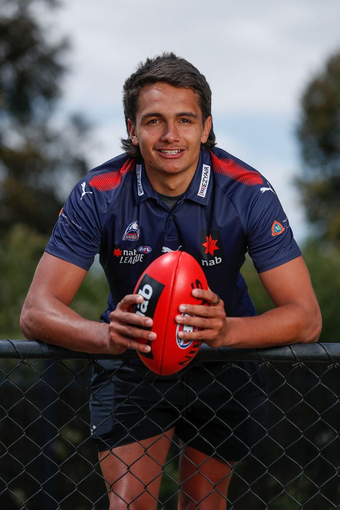 Oakleigh Chargers player in club guernsey holding a football