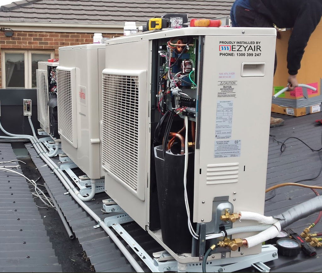 Outdoor air conditioning units being installed on a rooftop frame with a panel open